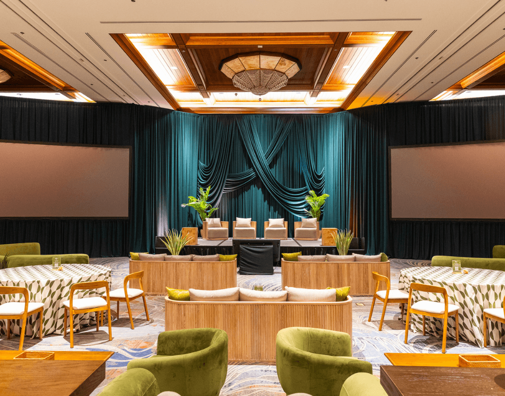 A furnished event stage with lounge seating and dramatic draping